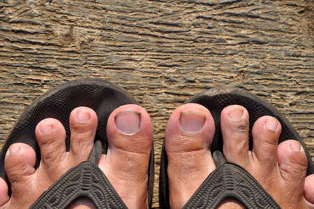 Close up of asian feet using sandal on cement floor. The soles of his feet are wide because he rarely uses shoesの写真素材