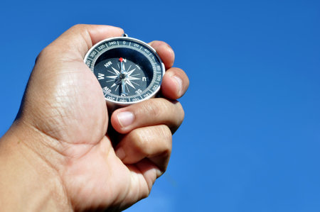 Hand holding the navigation compass blue sky background