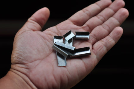 Close-up of male hands holding staples on black backgroundの写真素材