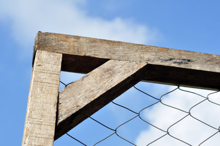 Wire fence with wooden frame blue sky backgroundの写真素材