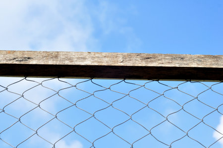Wire fence with wooden frame blue sky backgroundの写真素材