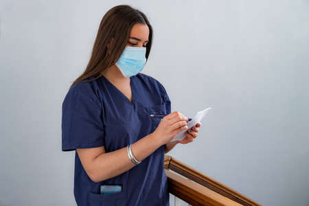 Young doctor writing a prescription or filling out a medical form while standing in the clinic