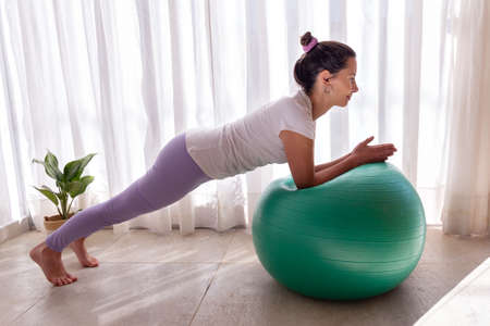 young woman in a yoga and pilates studio, strengthening abdominals, arms and legs.の写真素材