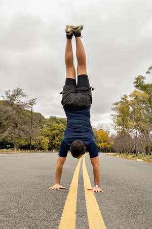 man doing a handstand in the middle of the road