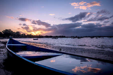 blue boat on the sunset, reflection of the clouds on the waterの写真素材