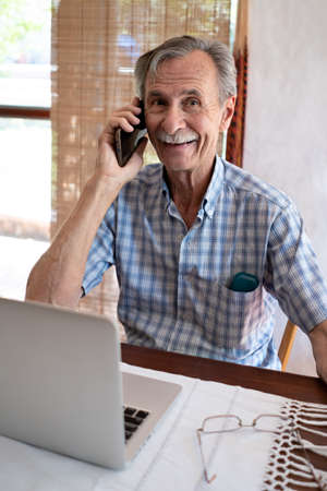 Mature man shopping online on laptop, using credit card at home.