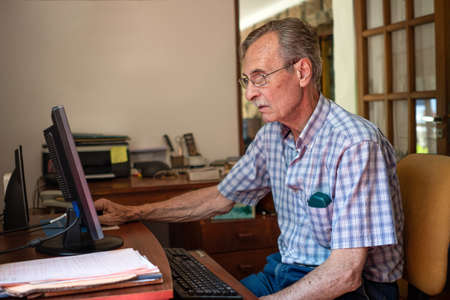 Mature man shopping online on laptop, using credit card at home.