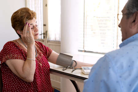 the husband puts the blood pressure measuring device on his wife who is feeling sick
