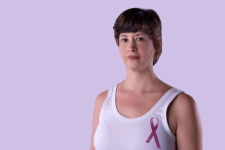Portrait of woman in a white T-shirt with a pink ribbon, symbol of International Breast Cancer Day.の写真素材