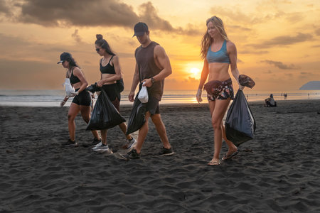 Team of vigorous recycling volunteers collecting plastic rubbish into bagsの写真素材