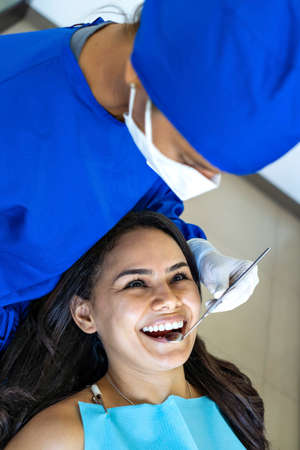 Young male patient visiting dentist office. Short Hair man with healthy straight white teeth sitting at dental chair and waiting his doctor. Dental clinic background for copy space text.の写真素材