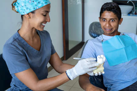 Young male patient visiting dentist office. Short Hair man with healthy straight white teeth sitting at dental chair and waiting his doctor. Dental clinic background for copy space text.の写真素材