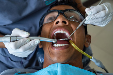 Male patient visits dental office. Dentist wearing rubber protective gloves performs dental treatment.の写真素材