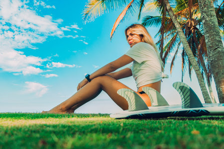 Portrait of pretty young girl sitting with a surfboard watching the sea.の写真素材