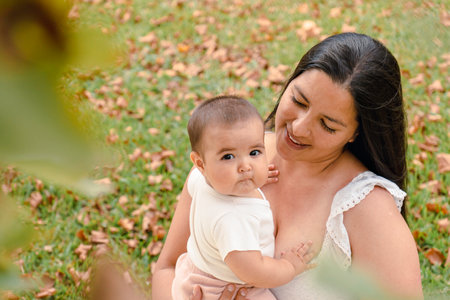 Portrait of attractive hispanic mother with her baby in a park. Baby looking at camera.の写真素材