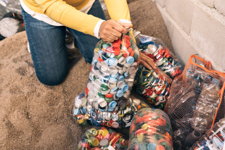 Close-up detail of a woman's hands sorting large amount of colorful plastic bottle caps. Recycling center.の写真素材