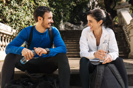Man and woman resting together after jogging sitting on the steps of a park.の写真素材