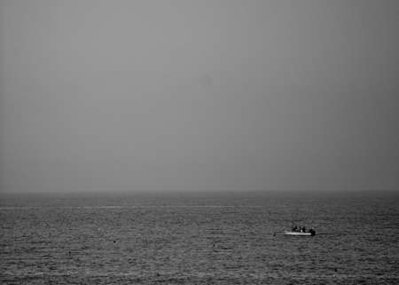 Lonely fishing boat in a white and black sea in Porto San Giorgioの写真素材