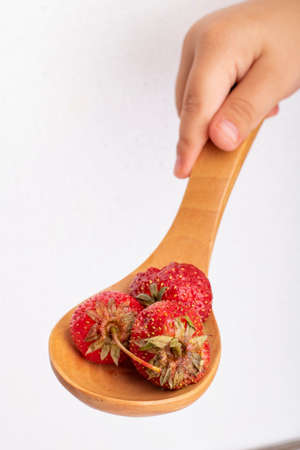 girl holding wooden spoon with strawberries, dessert for breakfastの写真素材