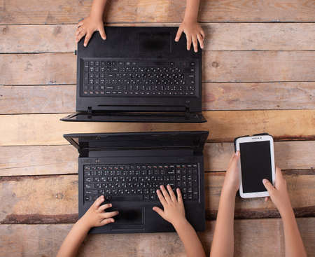 girl's hands lying on a wooden table, sitting at computerの写真素材