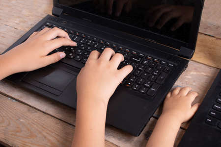 kids hands lying on a laptop, sitting at computerの写真素材