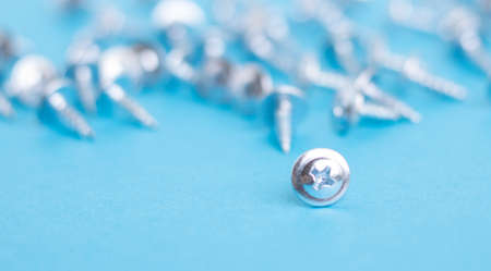Many screws on blue paper, blurred backgroundの写真素材