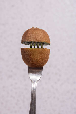 Two fresh halves of kiwi on fork, vertical photo