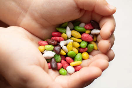 Girl holding Candy sweet background. Colorful sunflower seeds in a sweet glaze close-up on a white background as a texture.の写真素材