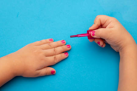children's manicure. Children's hands paint their nails with Colorful nail polish. Red manicure on childish nails.の写真素材