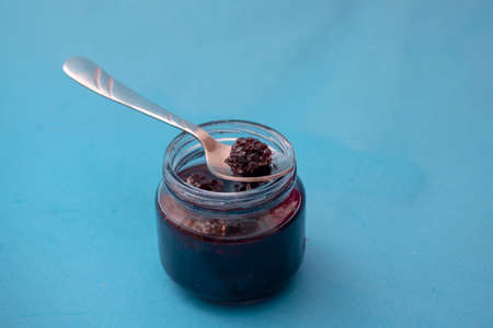 Homemade blackberry jelly in jar on blue paper with spoonの写真素材