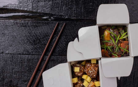Delicious wok noodles box container with udon and chicken on wooden table. Chinese and asian takeaway fast food,flat layの写真素材