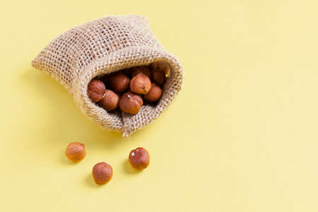 Hazelnuts, filbert in burlap sack on wooden backdrop. heap or stack of hazelnuts. healty food in eco sackcloth bag, zero wasteの写真素材