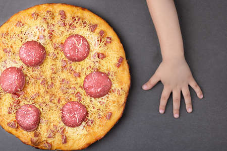 homemade margarita pizza, kids hands near cheese pizza on table, place for textの写真素材