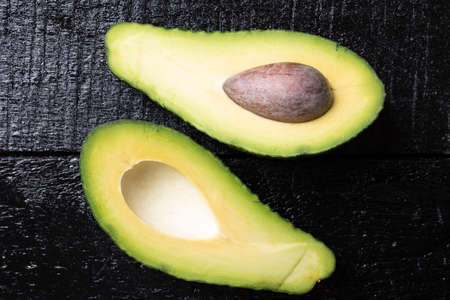 Avocado fruit on a black wood background. Top view and copy space