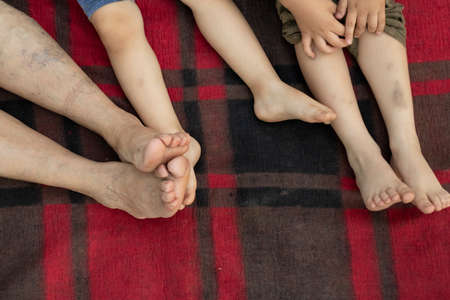 Close up of bare legs laying on red plaid blanket, picnic rug. resting in summer day in the park