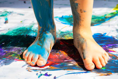 painted kids legs on bright paper, painting feetの写真素材