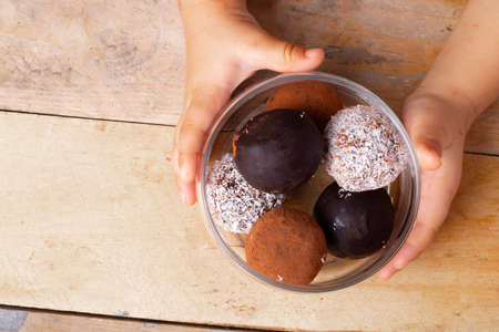Baby holding healthy energy chocolate balls glass bottle, top view and place for text on wooden...