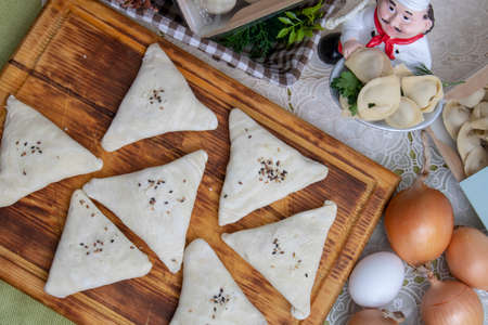 raw samosa on a plate with eggs and lettuce on a wooden table. horizontal close-up. flat layの写真素材