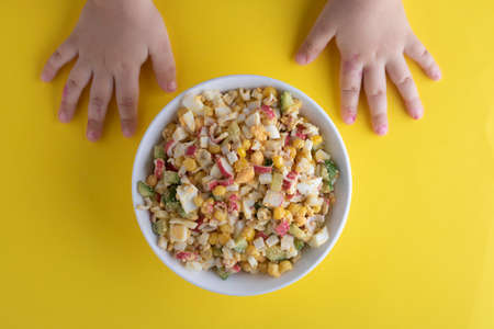 Colorful salad and kids hands, strawberries, almonds and sesame seeds, top view. vegan food concept.