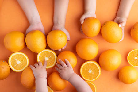 Tangerines in kids hands, flat lay. preparing for Christmas time. Holding orangesの写真素材
