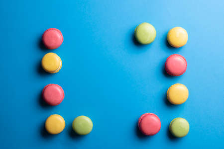 Macarons frame, copy space in center. Macaroons on blue background. Top view or flat lay.