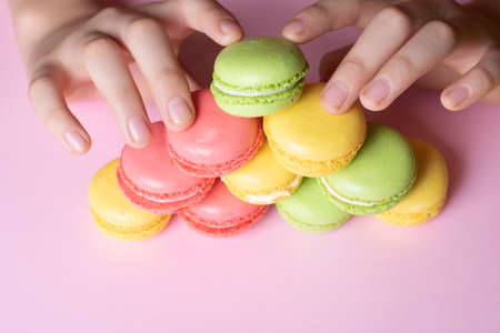 Boy holding colorful French macarons in hands, pyramid concept