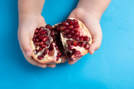 little girl holding open ripe pomegranate closeup. Top viewの写真素材