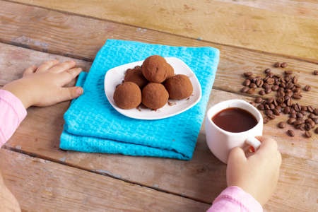 vegan vegetarian raw snack, kid holding cup of coffee and energy ballsの写真素材
