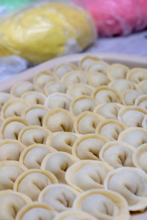 Raw pelmeni or dumplings with meat, colorful dough backgroundの写真素材