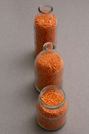 Glass bottles with red lentils on a table in rowの写真素材