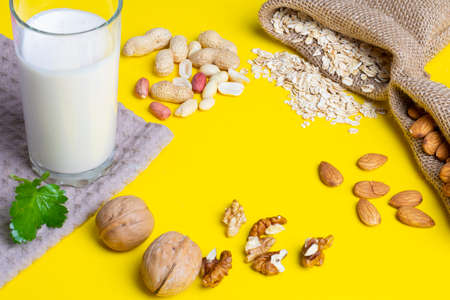 oat milk in glass on yellow background. Keto nuts in burlap bagsの写真素材