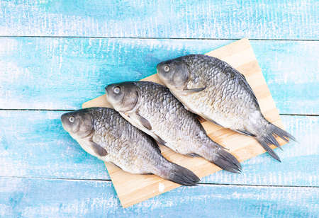 fresh raw three sea fish on wooden chopping board, flat lay. Place for textの写真素材