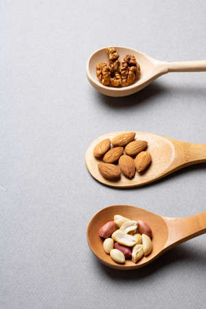 Three wooden spoons with nuts, minimal image. Vertical photoの写真素材