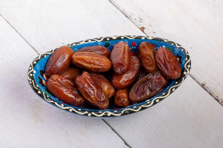 Dried Dates fruit in a bowl closeup on wooden table